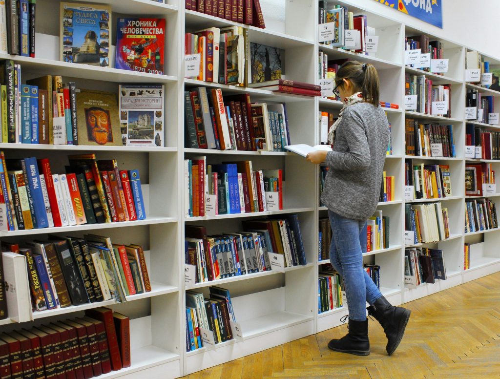 Student searching library shelves for ATI TEAS 7 Test Bank study materials